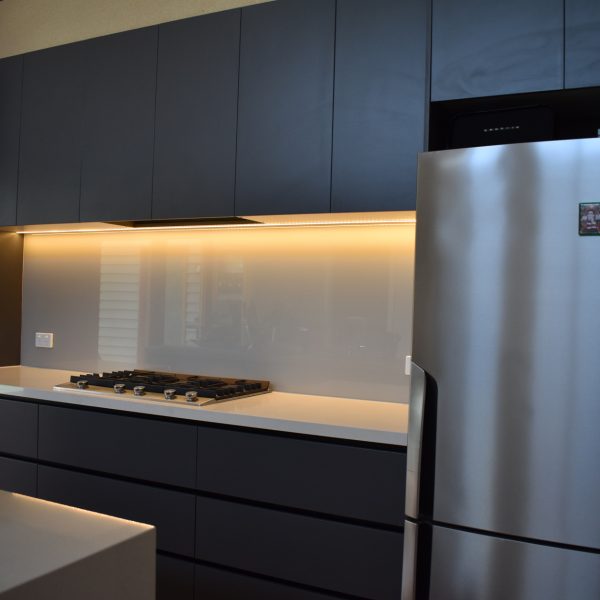 dark colour scheme kitchen with light grey glass splashback