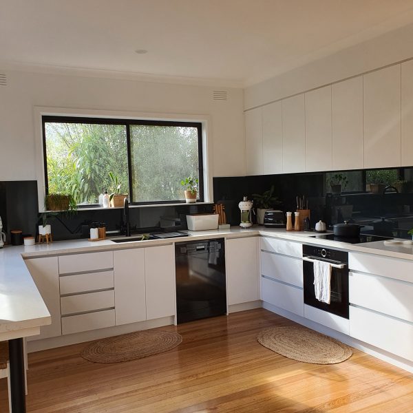 modern white kitchen with black glass splashback