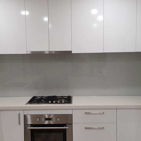 modern white kitchen with grey glass splashback