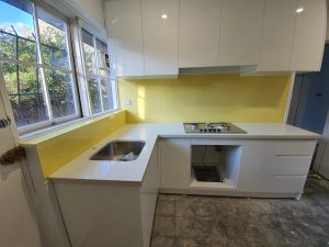 mustard coloured glass splashback in white kitchen