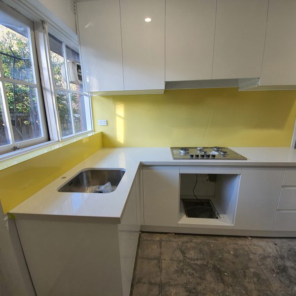 mustard coloured glass splashback in white kitchen