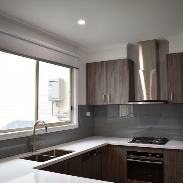 grey coloured glass splashback in timber look kitchen